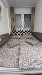 a large bed with two pillows in a bedroom at Baba néni nyaralója in Szarvas