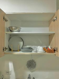 a kitchen shelf with bowls and dishes on it at Yugen Studio in Davao City