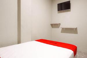 a bedroom with a white bed with a red blanket at RedDoorz at Deluxe Hotel near Terminal Purabaya Bungurasih in Sidoarjo