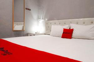 a large white bed with a red pillow on it at RedDoorz at Deluxe Hotel near Terminal Purabaya Bungurasih in Sidoarjo +18 photos