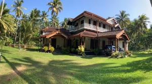 a house with palm trees in front of a yard at Mishthana Canal Resort in Bentota