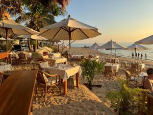 a beach with tables and chairs and umbrellas at Tree Space Lanta Pool Stay Quiet & Near Beach in Ko Lanta