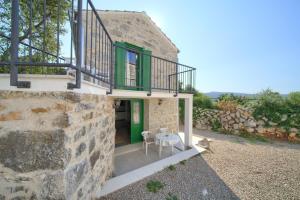 a stone house with a green door and a table at Kamena vila in Kornić