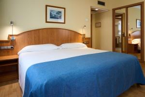 a bedroom with a large bed with a blue blanket at II Castillas Madrid in Madrid