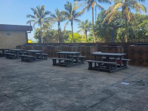a group of picnic tables with palm trees in the background at Amanzi 1304 in Amanzimtoti