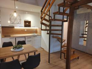 a kitchen and dining room with a wooden table and a spiral staircase at Garden 022 in Vrdnik