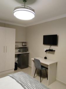 a bedroom with a bed and a desk and a television at Indawo Guesthouse in Bloemfontein