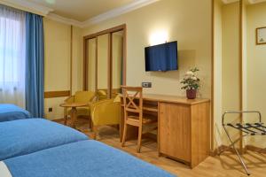a hotel room with a desk and a tv at II Castillas Madrid in Madrid
