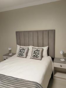 a bedroom with a white bed with two pillows on it at Indawo Guesthouse in Bloemfontein +19 photos