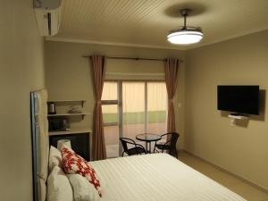 a bedroom with a bed and a tv and a table at Indawo Guesthouse in Bloemfontein