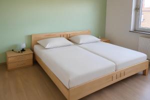 a bed with two white pillows and a wooden headboard at Ferienwohnung Saller in Weißenbrunn
