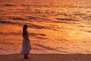 a woman in a white dress walking on the beach at Marari Beach Resort Alleppey - A CGH Earth Experience in Alleppey