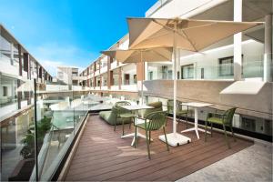 a balcony with tables and chairs and an umbrella at Hotel Coral Cotillo Reef in El Cotillo