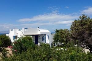 a white house with trees in front of it at Villa H - Kamari Village in Kastraki