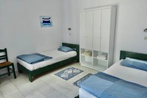 a bedroom with two beds and a cabinet and a chair at Villa H - Kamari Village in Kastraki +23 photos