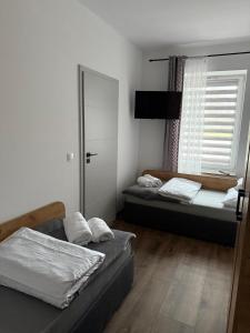 two beds in a room with a window at Hostel Granat in Czekanów +8 photos