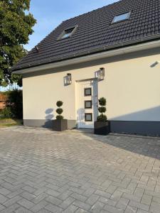 a white building with a door and two plants at Ferienwohnung-Karwe in Karwe