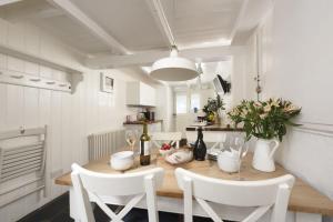 a dining room with a wooden table and white chairs at Walters on The Digey - 100m to beach - pets allowed in St Ives