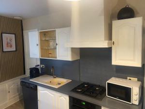 a kitchen with white cabinets and a sink and a microwave at Le Loft Dolois, Maison Loft in Dole