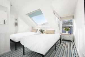 two beds in a room with a window at Walters on The Digey - 100m to beach - pets allowed in St Ives