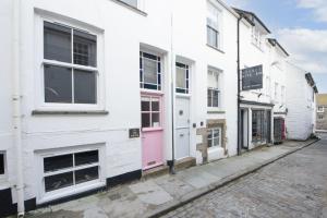 a white building with a pink door on a street at Walters on The Digey - 100m to beach - pets allowed in St Ives