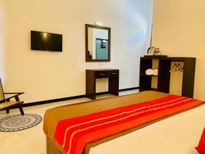a bedroom with a bed and a mirror and a chair at Ayubowan Yala in Tissamaharama +9 photos