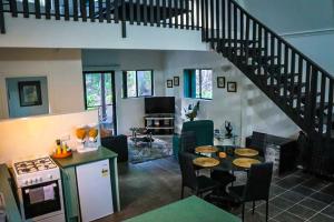 a living room with a staircase and a kitchen with a table at GREEN TREES CHALET Australia Zoo close by in Landsborough