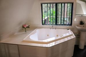 a large bath tub in a bathroom with a sink at GREEN TREES CHALET Australia Zoo close by in Landsborough