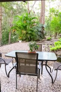 a table and chairs with a potted plant on a patio at GREEN TREES CHALET Australia Zoo close by in Landsborough