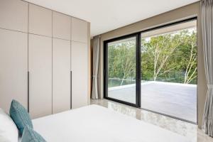 a bedroom with a large window and a bed at Dapple Villa in Na Mueang
