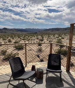 two chairs sitting on a balcony looking at the desert at Treehouse in Joshua Tree