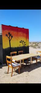 a picnic table and two chairs in front of a painting at Treehouse in Joshua Tree +2 photos