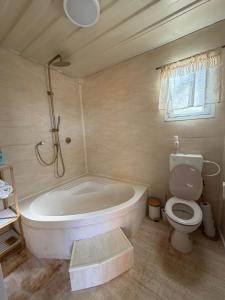 a bathroom with a white tub and a toilet at הzimער של ביטון in Merhav Am