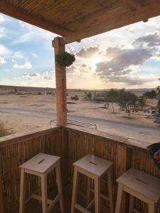 a porch with two stools and a view of the desert at הzimער של ביטון in Merhav Am