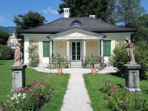 a small white house with green shutters and flowers at Rosenvilla - Musikerschlössl in Bad Ischl