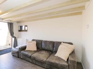 a living room with a brown leather couch at Barn Cottage with pre booked use of Indoor Swimming Pool in Frome
