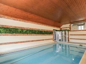 a swimming pool with plants on the walls and a wooden ceiling at Barn Cottage with pre booked use of Indoor Swimming Pool in Frome