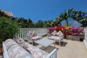 a patio with chairs and a table and flowers at Katamanda A1 Mila Pool Villa Kata Beach in Kata Beach