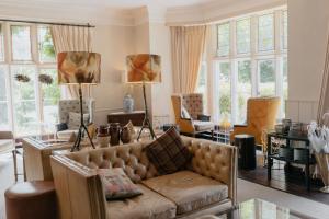 a living room with a couch and chairs and windows at The Coed-Y-Mwstwr Hotel in Bridgend
