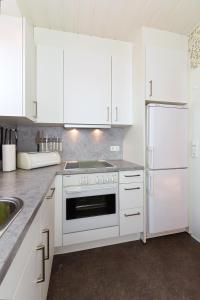 a kitchen with white cabinets and a white refrigerator at Ferienhaus Blauer Anker in Bensersiel +16 photos
