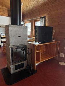 a living room with a fireplace and a television at Skutstuga 2 - Gruvbacken Huså in Järpen