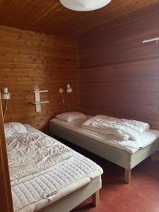 two beds in a room with wooden walls at Skutstuga 2 - Gruvbacken Huså in Järpen