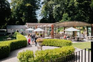a group of people walking through a garden with umbrellas at The Coed-Y-Mwstwr Hotel in Bridgend