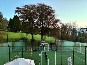 a tennis court with a net and a tennis court at The Coed-Y-Mwstwr Hotel in Bridgend