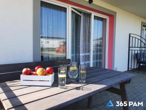 a wooden table with a bowl of apples and glasses at 365PAM - Kolory Lata - KLIMATYZACJA, PLAC ZABAW, GRILL in Sarbinowo +38 photos