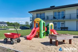 a playground with slides and a cart in front of a house at 365PAM - Kolory Lata - KLIMATYZACJA, PLAC ZABAW, GRILL in Sarbinowo