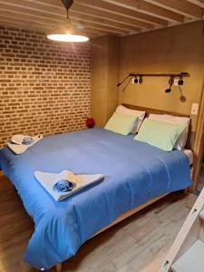 a large blue bed in a room with a brick wall at Chez Théo in Trois-Ponts