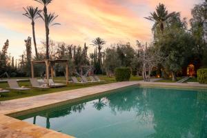 a swimming pool in a yard with palm trees at Bab Akoul Palmeraie - Boutique Hotel & Spa in Marrakesh