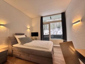 a bedroom with a bed and a large window at Kurhaus im Harz - Bad Harzburg in Bad Harzburg