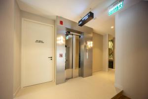 a hallway with a white door and a exit sign at GinGin Hotel, Trang Old Town in Trang